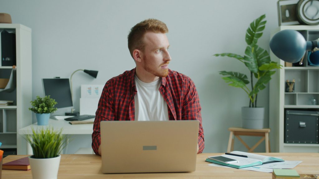 Imposter syndrome man sat at laptop